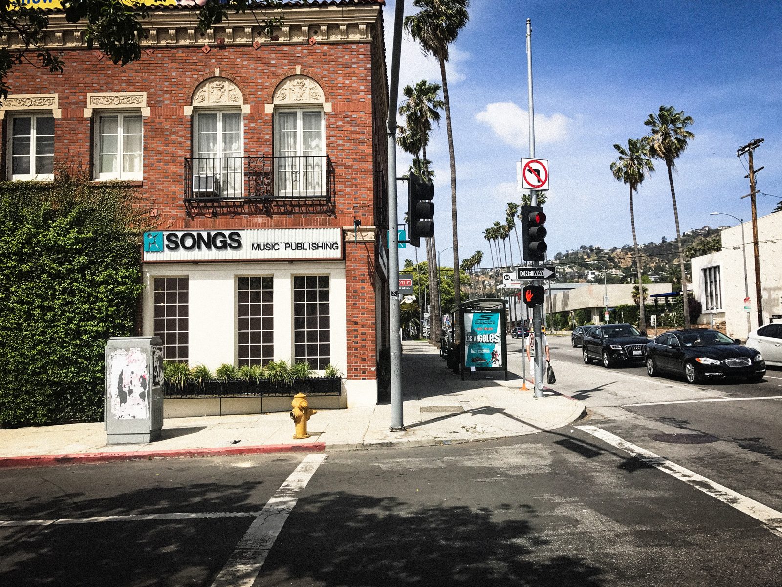 The SONGS Music Publishing building on a West Hollywood corner, palm trees and traffic lights beyond.